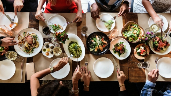 overhead view of table of food and people eating