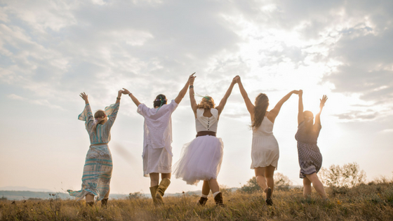 group of girls holding hands and walking together in a field